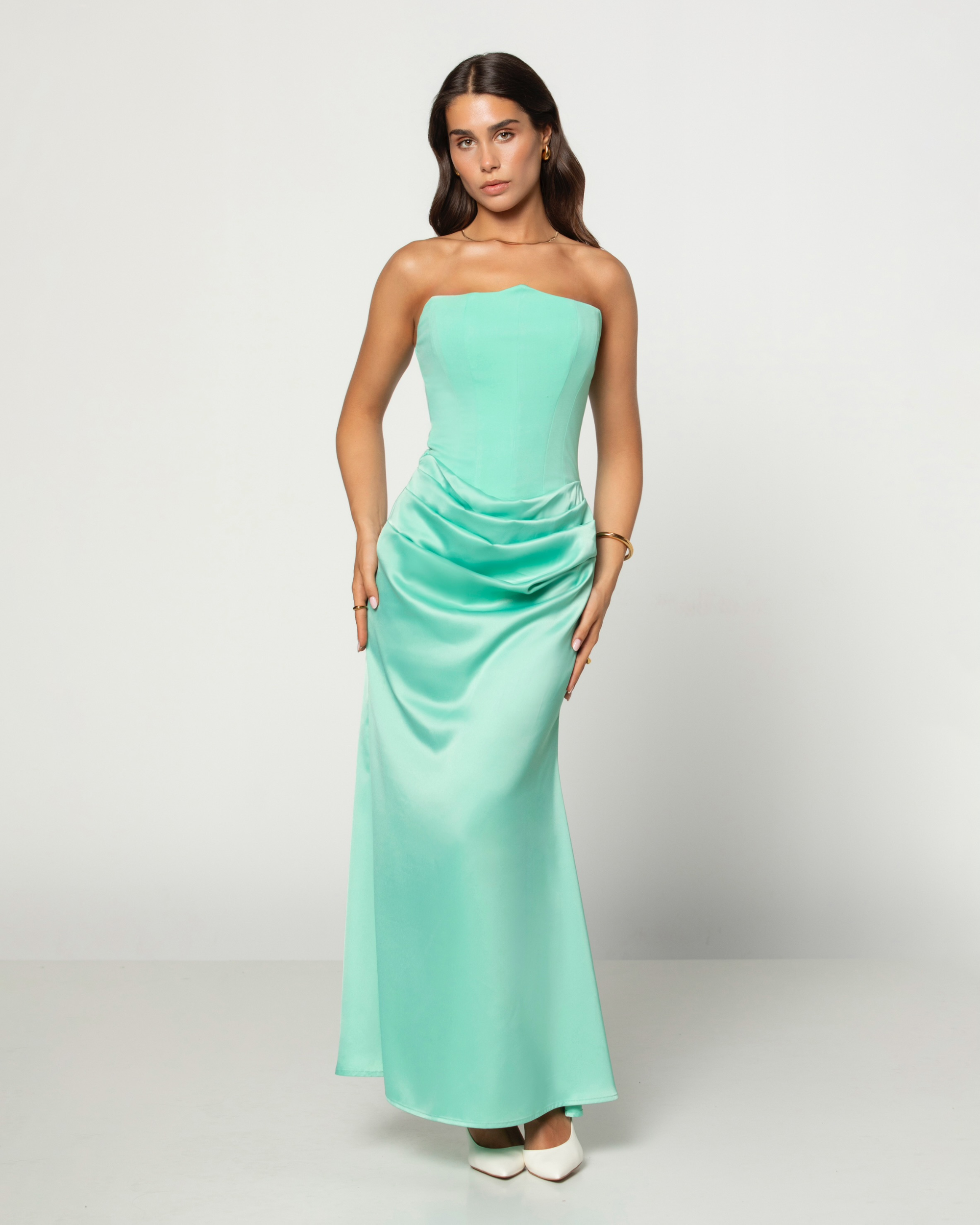 Woman wearing a strapless mint green gown on a white background
