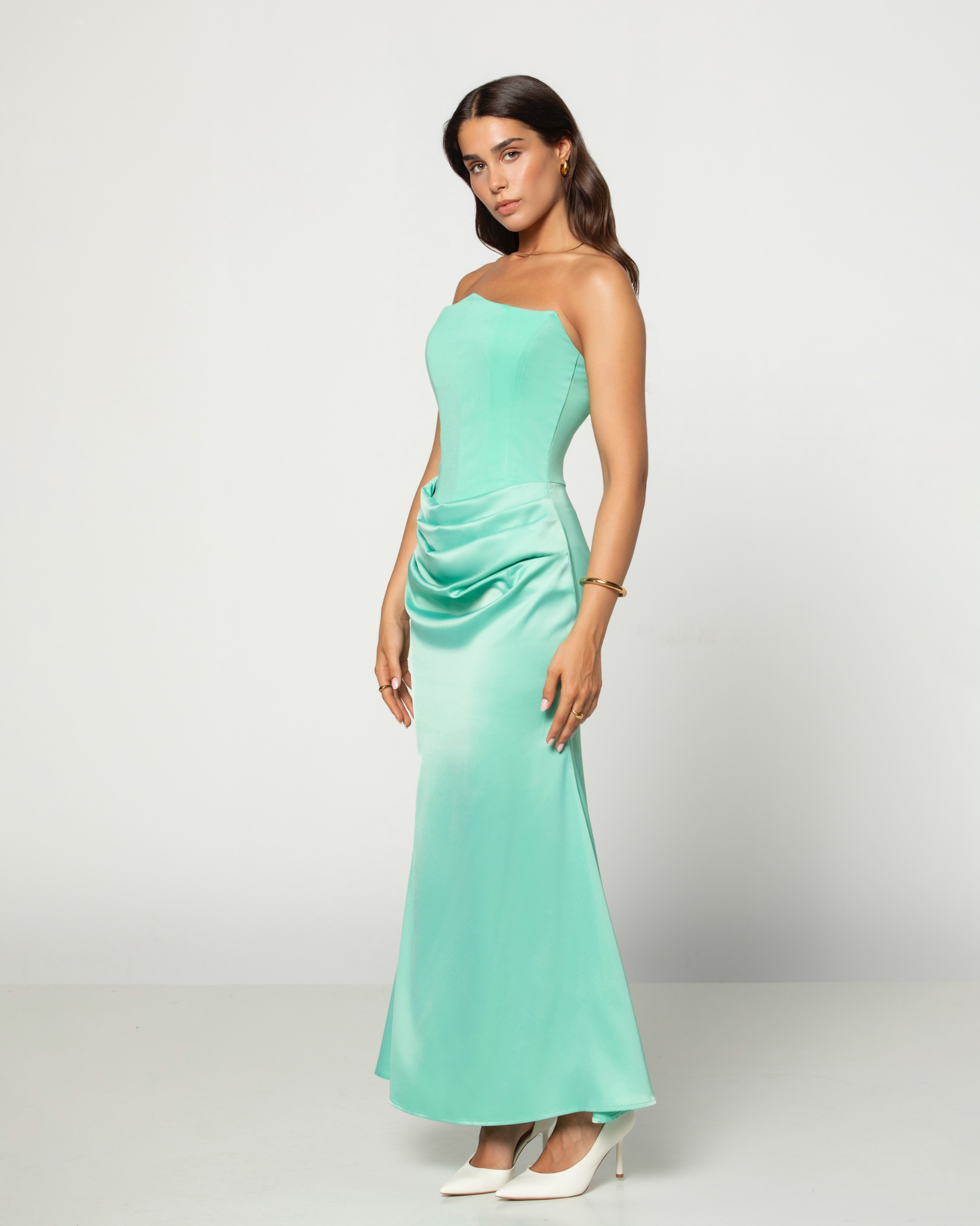 Woman wearing a mint green strapless gown on a white background